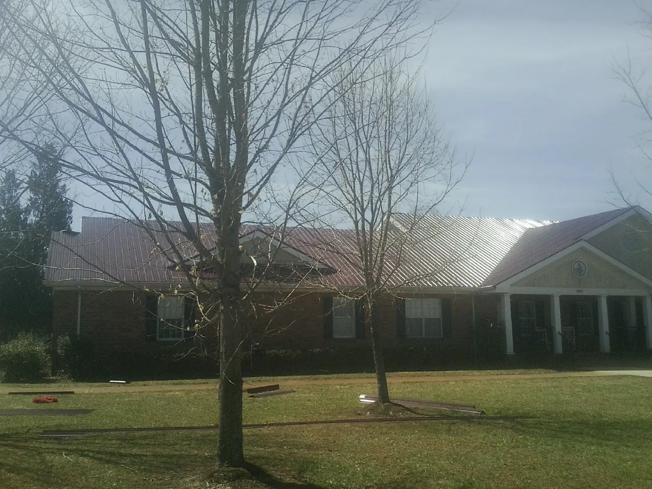 Red metal roof on a brick building seen from the front lawn in Lonsdale
