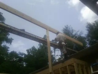 Carpenter setting a ridge beam over a new addition frame — Ice Dam Removal by Roofing Brothers in Lonsdale