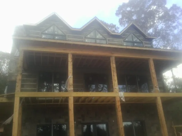 Dormers and porch framing on a large log home under construction — Roof Coating work by our crew in Lonsdale