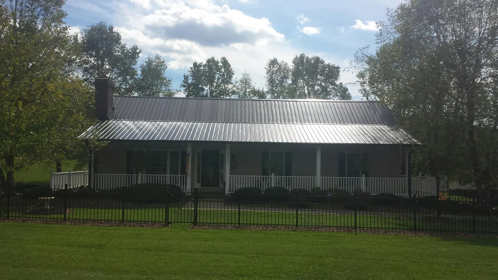 Gray metal roof on a brick ranch with a full width front porch — Gutter Guard Installation work by our crew in Lonsdale